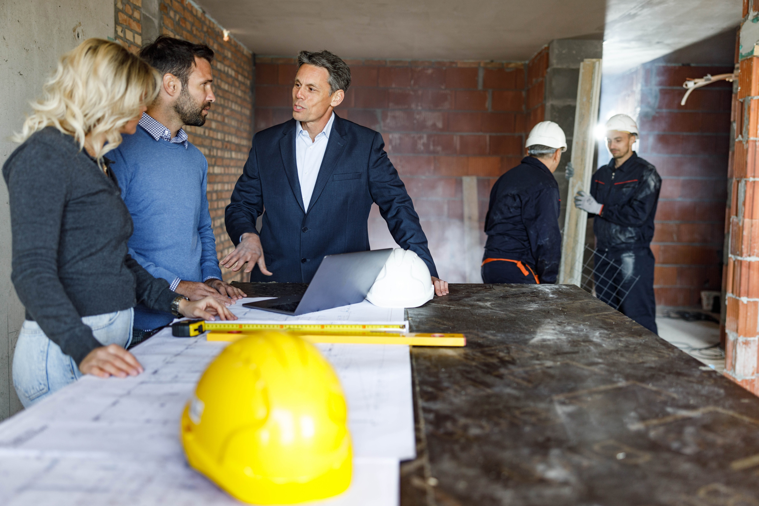 Building contractor and his customers talking about renovation plans at construction site.